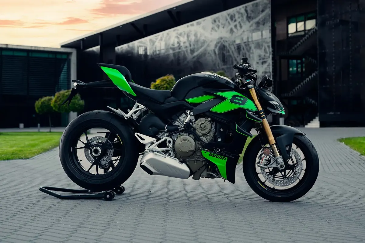 Must-roheline Ducati Streetfighter V4 kivisillutisel kaasaegse hoone ees